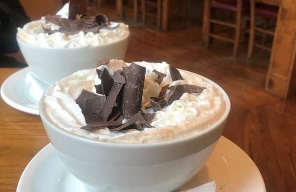 Giants bowls of hot chocolate topped with whipped cream and chocolate shavings