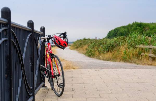 A bicycle resting against a rail on a pathway.