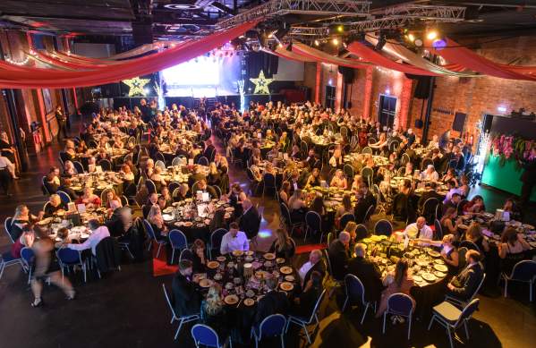 An event hall filled with people at tables and a stage in the distance.