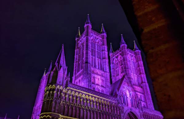 Lincoln Cathedral illuminated in purple light at night.