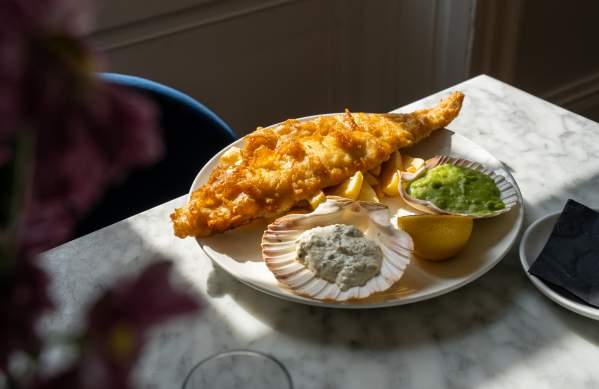 A plate of well decorated fish and chips placed on a restaurant table.