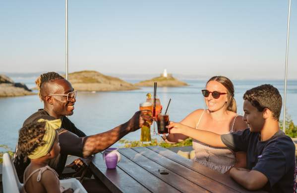 Family toasting their glasses with coast in the background