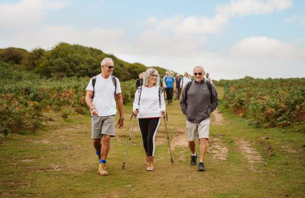 group of older people chatting and hiking along gower with hiking equipment