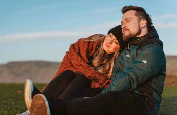 A couple (man and woman) in winter clothes watching a sunset.