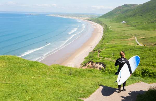 Surfer walking down to Rhossili Bay Beach