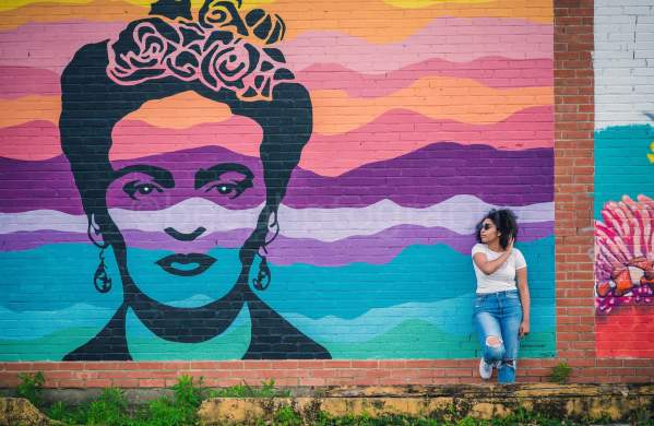 Woman leaning on the wall next to the Frida Kahlo mural in downtown Beaumont