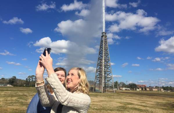 Visitors take a selfie at Spindletop as the gusher blows