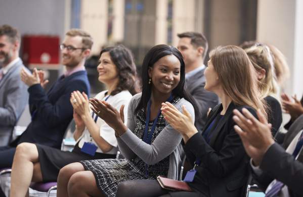 Attendees sitting in a meeting clapping