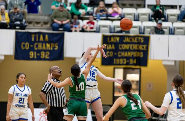 Photo of a two girl basketball teams tipping off to start the game at the Brownwood Coliseum