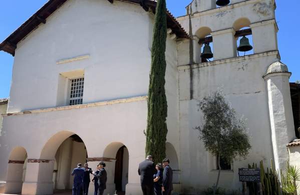San Juan Bautista Mission. People stand in front of the Mission entryway and Bell Tower.