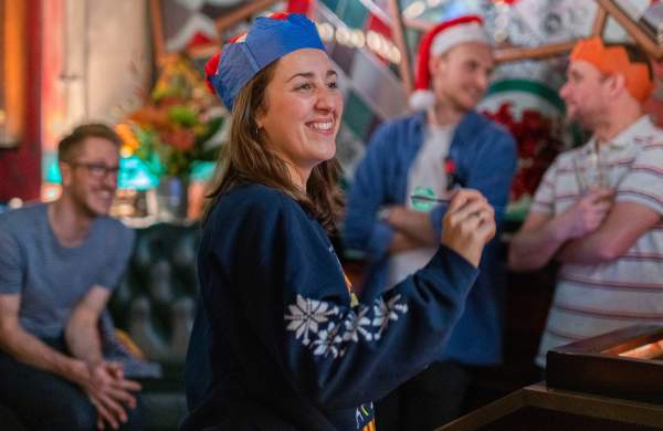 People wearing Christmas party hats playing darts - Credit Flight Club
