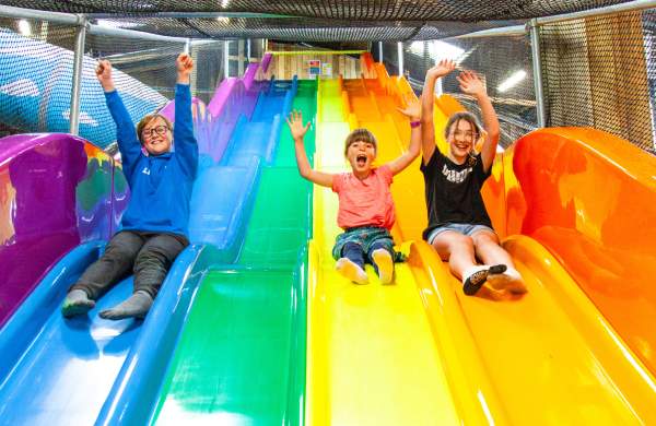 3 children coming down a wavy rainbow slide at Noah's Ark Zoo Farm - Credit Noah's Ark Zoo Farm