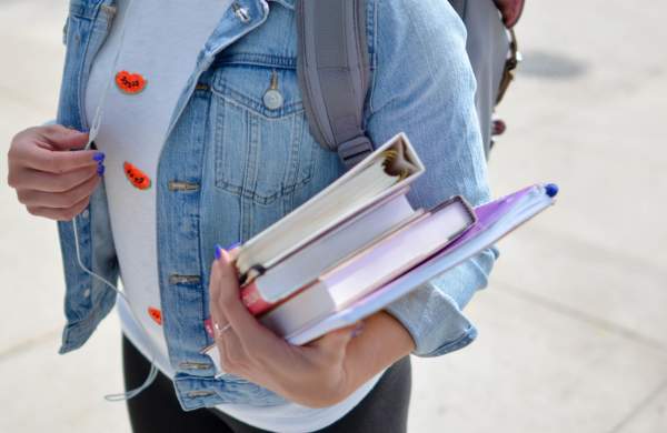 A female university student carrying a handful of books