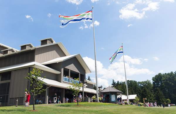A theater building with a blue sky above, green grass and flags waving above it.