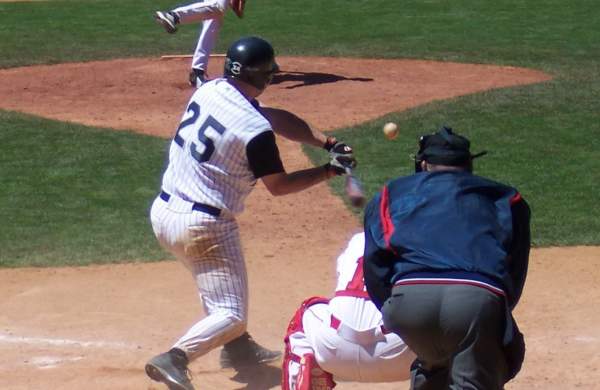an image of a baseball player in a white uniform with the number 25 swinging his bat at a ball with an umpire and catcher behind him