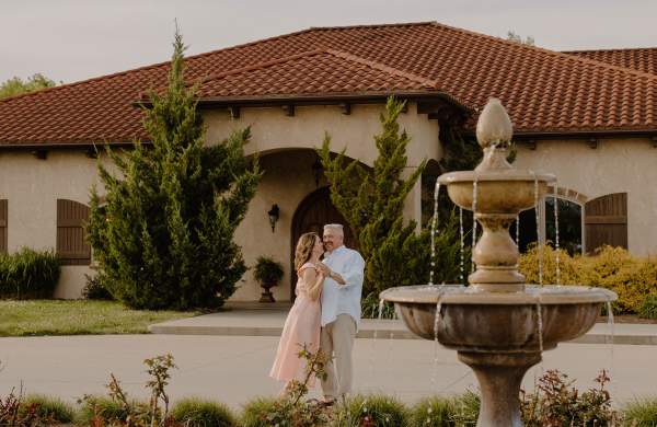 Couple dancing in front of Tuscan Hills Winery with fountain in foreground