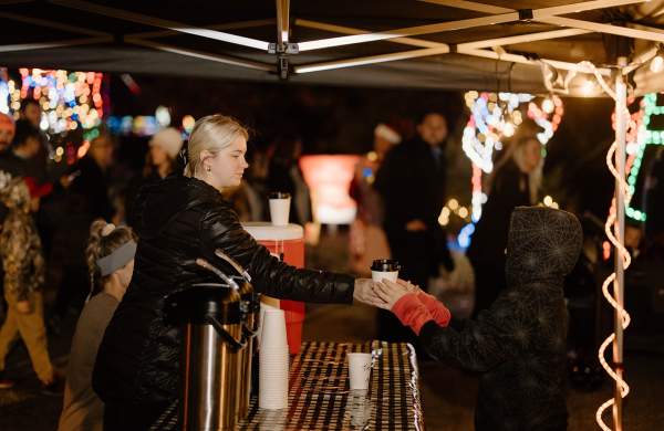 Child taking hot cocoa from vendor at Walking Through Wonderland Event