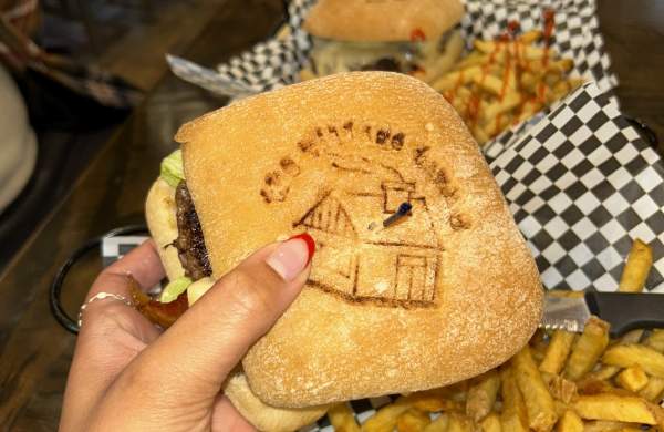 a hand holding a burger from the Village Tavern in Mill Creek, PA