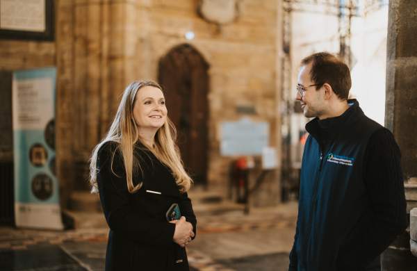 a woman smiles at a tour guide in Boston stump with church walls in background