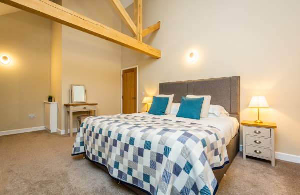 a bedroom with a large fitted bed, and wooden beams on the ceiling.