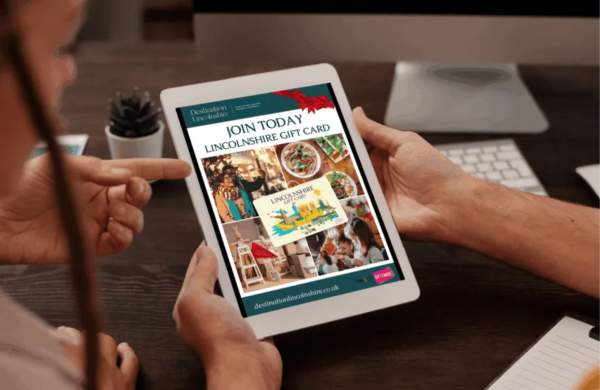 A mockup of a Lincolnshire Gift Card advert on a tablet screen with two people looking at it