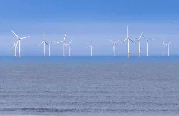 Offshore windfarms on the Lincolnshire Coast with a beach in the foreground under blue skies