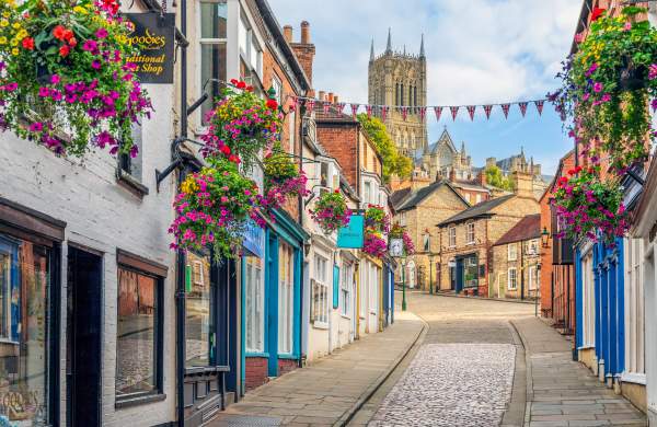 A cobbled street with colourful flowers and cathedral in the background