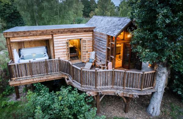 Exterior of a lodge in the woods with hottub