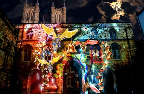 Exchequer Gate at night with a light display projected onto its front, with Lincoln Cathedral in the background
