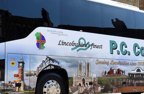 A side view of a PC Coaches Bus parked outside Lincoln Cathedral in the daylight