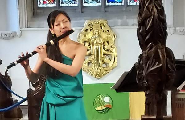 Asian woman in teal dress playing the flute