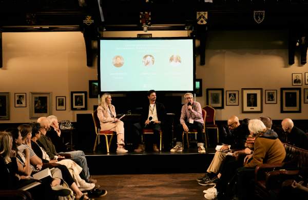 Three speakers talking to a audience at a conference in Cambridge