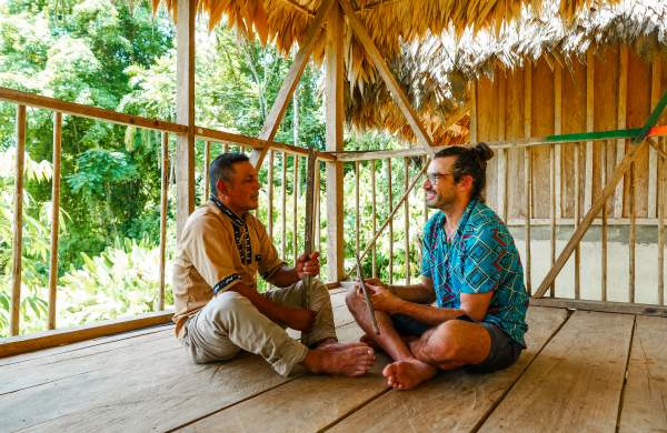 Naso Tjër Di man Interacting with a tourist inside a rural house in the community.