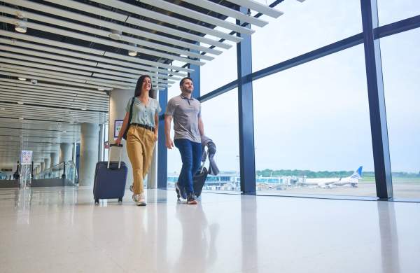 Pareja de turistas con maletas caminando en el Aeropuerto Internacional de Tocumen, Ciudad de Panamá