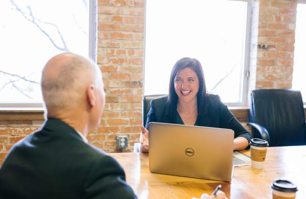 Two middle-aged professionals smile while collaborating during a business meeting