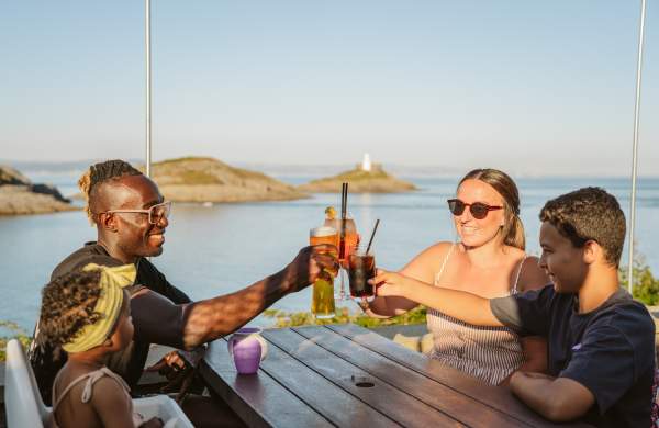 Family toasting their glasses with coast in the background