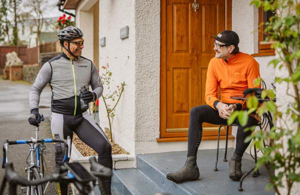 Two men in cycling clothes chatting to each other.