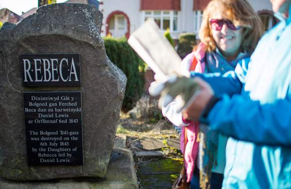 Walkers looking at a stone with a plaque commemorating the Rebecca Rioters.