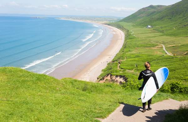 Surfer walking down to Rhossili Bay Beach