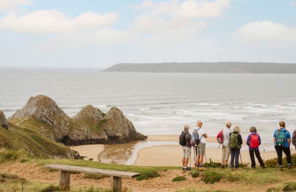 A group of walkers looking out at Three Cliffs Bay.