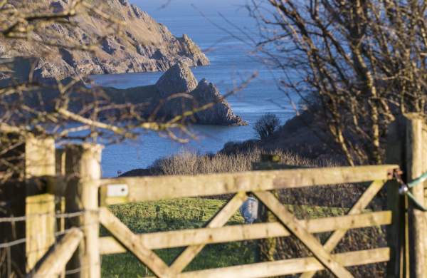 A gate in the countryside with Three Cliffs in the background.