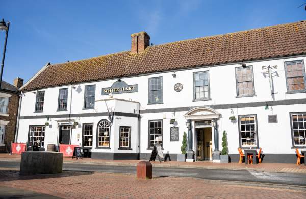outside of a white pub under blue skies with outdoor seating
