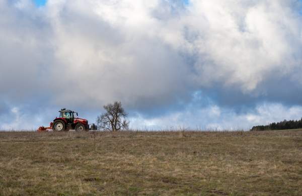 A tractor in an open field under a blue sky