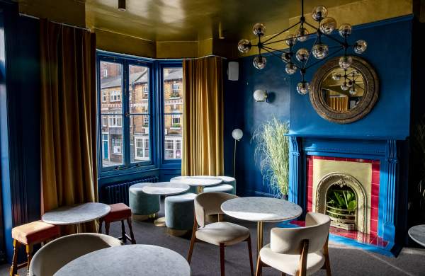 A hotel lounge with blue walls and marble tables with chairs