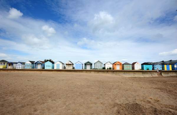 a line of beach huts with sand and blue skies