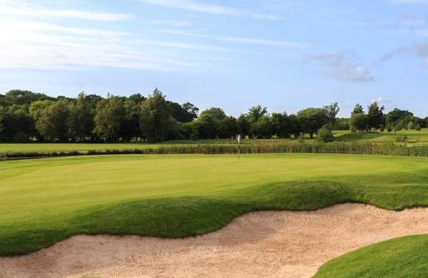 A golfing green with sand in foreground
