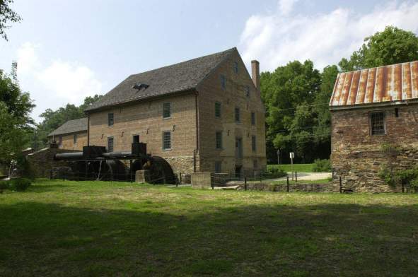 Four-story stone grist mill with tandem metal waterwheel at Aldie Mill Historic Park in Loudoun