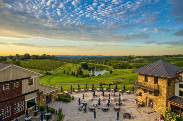 Aerial view of Stone Tower Winery's outdoor patio and rolling vineyard at sunset in Leesburg, Virginia.