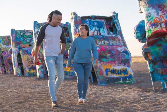 Couple at walking around the Cadillac's at Cadillac Ranch in Amarillo, TX