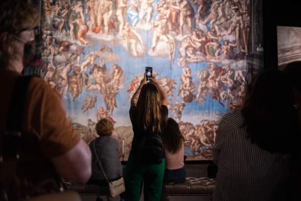 Woman taking photo at the Michelangelo's Sistine Chapel: The Exhibition